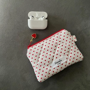 Close-up of quilted white cosmetic bag with red heart pattern and heart zipper pull