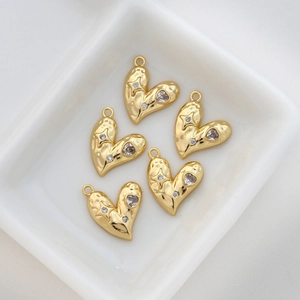 Detailed view of gold plated heart charms with sparkling cubic zirconia in white bowl