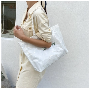 Side view of clear tote bag with white canvas insert and green Skinlly printed text