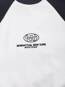 Close-up of NY Manhattan embroidery on white and navy blue raglan crewneck sweatshirt