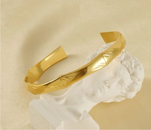 Artistic detail of gold bamboo cuff bracelet on a white gypsum statue background
