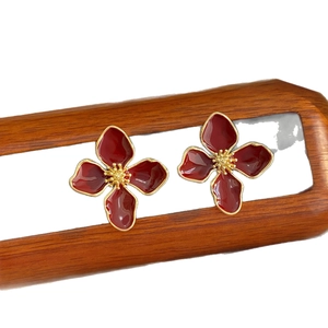 Vintage red enamel flower earrings on a wooden display stand with minimalist gold plating