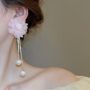 Detail of pink floral earrings with rhinestone tassels and pearls on a female model