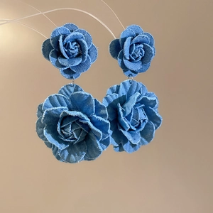 Close-up of blue denim fabric rose earrings showing detailed texture and floral design