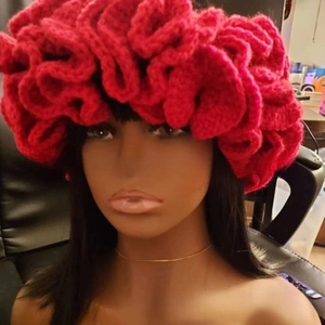 Close-up of red handcrafted knit hat with layered ruffle texture on a model head