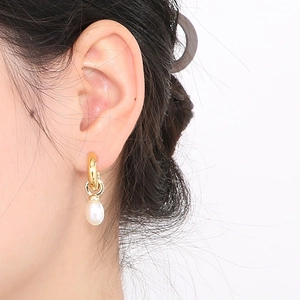 Gros plan de boucles d'oreilles créoles dorées en C avec perles blanches sur mannequin