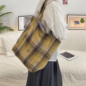 Detail of vintage wool plaid tote bag featuring yellow checkered pattern and metal logo