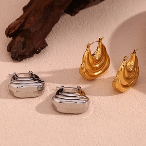 Close-up of layered boat-shaped hollow earrings in polished gold and silver finishes