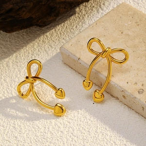 Close-up of gold-plated stainless steel bowknot earrings with heart-shaped pendants
