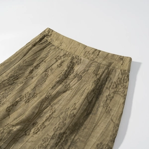 Detailed close-up of high-waisted olive green pleated fabric with floral branch print