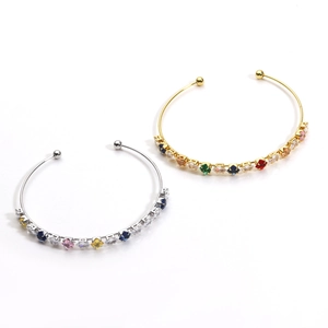 Detail view of gold and silver open bracelets with colorful synthetic gemstones