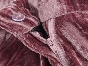 Detailed macro view of pink velvet suit fabric featuring resin buttons and zipper closure