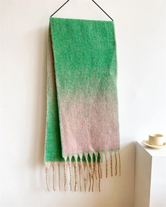 Detail of pink and green gradient scarf with tassels hanging on a black hanger