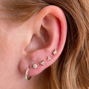 Golden geometric stud earrings set with sparkling zircon on ear model for a stylish look