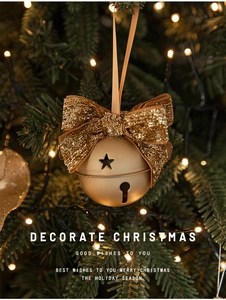 Close-up of golden Christmas bell with star cutouts and a glittery bow on a festive tree