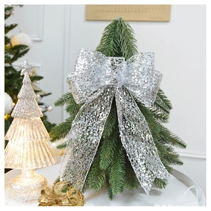 Silver glitter mesh bow topper detail on green Christmas tree with warm glowing background