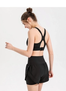 Detail of black sports bra with racerback buckle and layered shorts with side lettering
