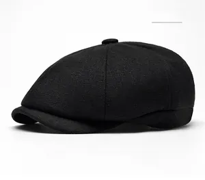 Detail view of a black wool newsboy cap showing stitched panels and top button texture