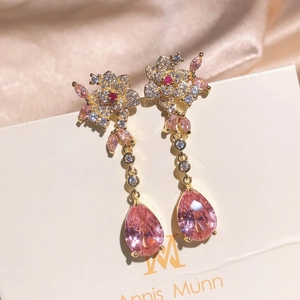 Macro shot of long flower earrings with pink teardrop crystal and gold settings