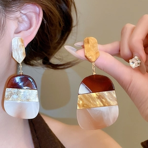 Macro detail of tortoiseshell marble pattern on geometric resin dangling earrings