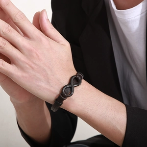 Close-up of brown braided leather bracelet with black matte infinity symbol on male wrist