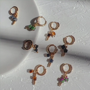 Macro view of French retro 18k gold hoop earrings with cube natural stone pendants