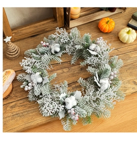 Detail of Christmas wreath with cotton, red berries and snow on a rustic wooden table