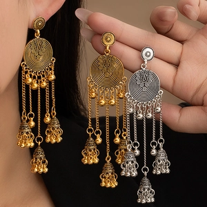 Macro detail of Bohemian tassel earrings with intricate flower carvings and small bells