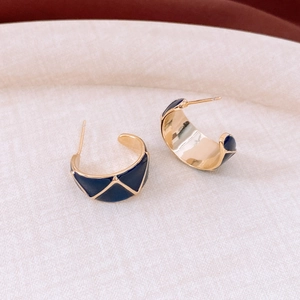 Detail of vintage 18k gold plated C-shape hoop earrings with blue enamel geometric pattern
