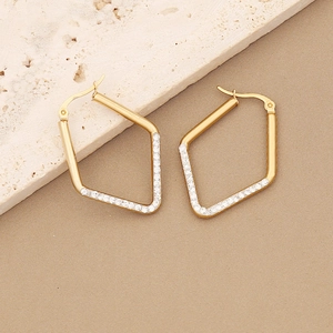 Macro shot of gold geometric earrings with pavé white zircon stones on silk fabric