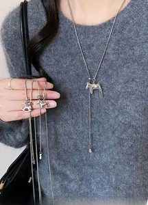 Silver horse pendant necklace with snake chain layered on a dark grey knitted sweater