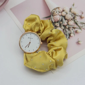 Detail of yellow satin scrunchie watch band with silver studs and rose gold dial