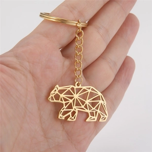 Golden stainless steel geometric bear keychain shown held by hand for size perspective