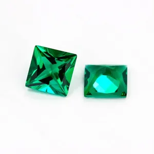 Two princess cut synthetic emerald gemstones with deep green color on white background