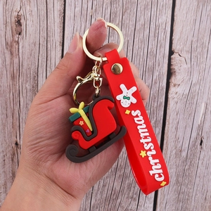 Close-up of Christmas sleigh PVC keychain with a red silicone wristband and holiday text