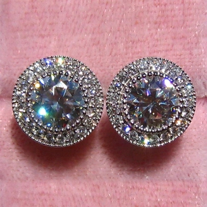 Close-up of sparkling halo stud earrings with round-cut center stone in silver finish