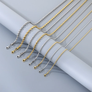Détail des chaînes torsadées en acier inoxydable doré et argenté sur support gris