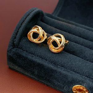 Vue macro de boucles d'oreilles torsadées dorées dans un écrin en velours noir