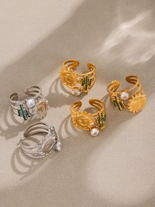 Detail of bohemian sun and cactus rings with green zircon on sand textured background