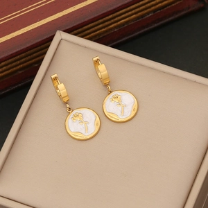 Golden hoop earrings with white enamel rose pendants displayed on a beige jewelry cushion