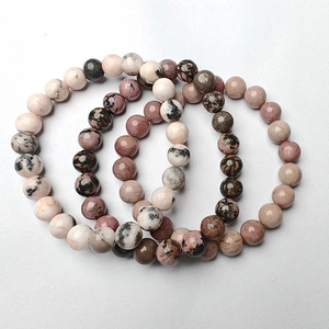 Close-up of stacked 8mm natural stone bead bracelets in pink, beige, and brown textures