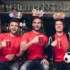 Three men wearing 2024 soccer party headbands with trophy and football icons in a bar