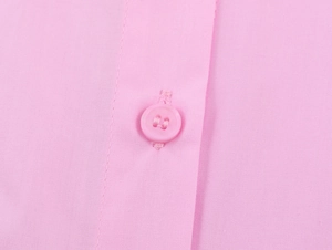 Macro detail of the pink poplin shirt featuring a matching four-hole button and stitching