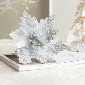 Silver glitter artificial Christmas flower placed on a minimalist magazine for holiday decor