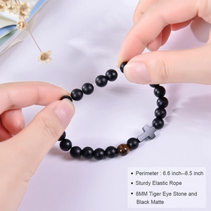 Detail of stretchable black matte and tiger eye stone bracelet with cross pendant