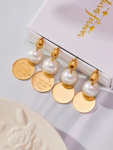Détail de boucles d'oreilles dorées 18 carats avec perles et pendentifs gravés