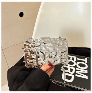 Detail of silver metallic clutch bag with hammer texture and elegant chain strap