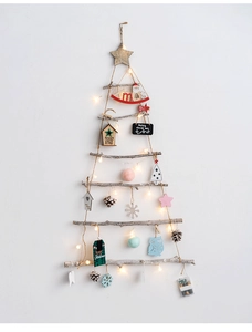 Detail of wooden branch wall-mounted Christmas tree with LED lights and star ornaments