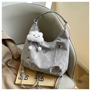 Detail of pleated silver grey handbag with metal butterfly and white fluffy cloud charm