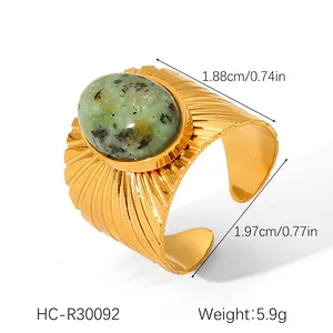 Macro shot of gold stainless steel ring with ribbed texture and green oval natural stone